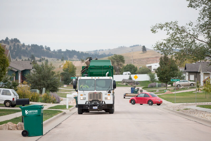 Picture of Kieffer Sanitation truck dumping 96 gallon carts in residential neighborhood.
