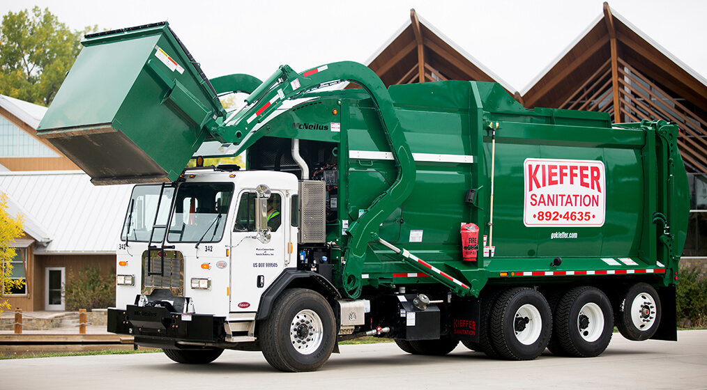 Photo of Kieffer sanitation truck lifting a commercial bin for dumping.