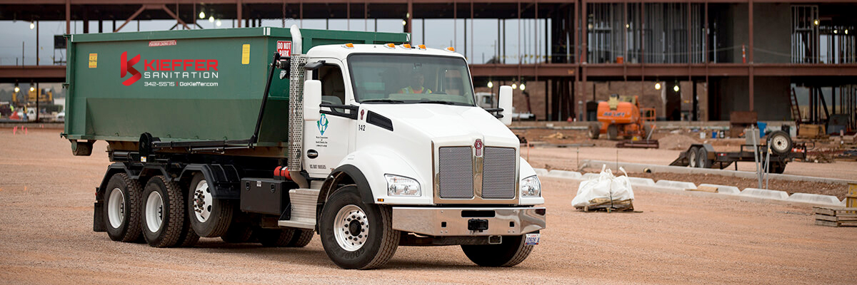 Picture of Kieffer Sanitation truck at construction site with roll-off bin.