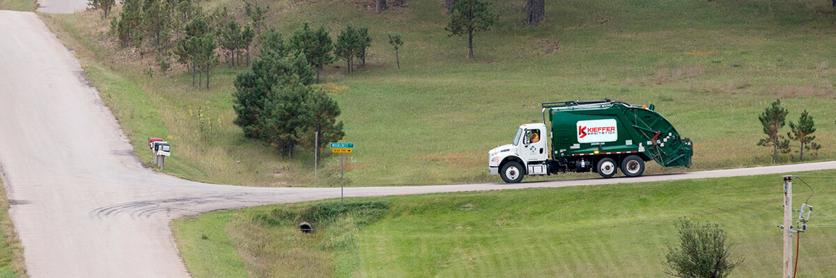 Photo of residential Kieffer Sanitation truck approaching intersection in residential area.