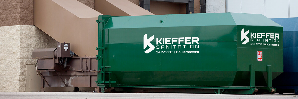 Photo of Kieffer Sanitation recycling compactor outside building.